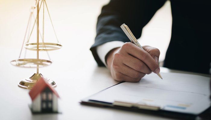 A hand writing on paper with scales of justice in background
